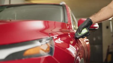 Profesyonel servis uzmanı araba boyasının kalınlığını koruyucu eldivenlerle test ediyor. Kalite kontrol. Detaylı araçta arabanın boyasının kalınlığını ölçen müfettiş.