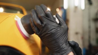 Car detailing and polishing concept. Auto detailing service, polishing of the car. Close up view of hands of man worker, polishing hood and body of modern luxury car with orbital polisher and wax