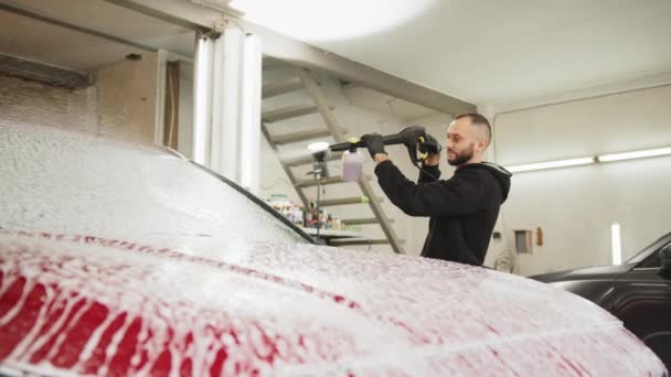 자동차 노동자가 현대식붉은 자동차 후드를 청소하는 서비스 스테이션 압축성 로손으로 — 비디오