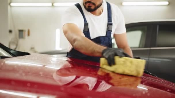 洗车和详细的概念 年轻而浓密的留胡子男工手拿着海绵 用肥皂清洗红色的车篷 — 图库视频影像
