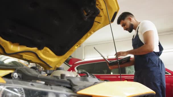 Young Man Car Mechanic Maintains Vehicle Using Diagnostic Laptop Computer — Stockvideo