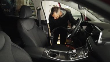 Araba süpürgesinin detayları. Kirli araba için elektrikli süpürge kullanan profesyonel genç bir işçi. Araba servisi çalışanı oto koltuğunu yıkamak için elektrikli süpürge kullanıyor..