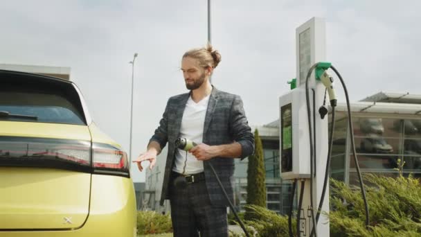 生态友好型现代绿色交通 电动车旁边的希斯特时髦男人 有人在公共收费站给电动车充电 电动车充电式港口塞车 — 图库视频影像