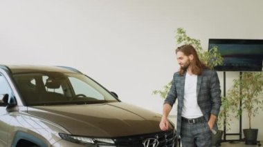 LVIV, UKRAINE - 20 Temmuz 2022: Showroom ve araba galerisi Hyundai. Yandan bakıldığında mutlu iş adamı erkek müşteri. Genç adam yeni arabaya bakıyor. Araba galerisinde tüketici