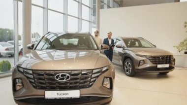 LVIV, UKRAINE - 20 Temmuz 2022: Showroom ve araba galerisi Hyundai. Başarılı bir orta yaşlı iş adamı araba galerisinde genç ve yakışıklı bir müşteriye araba satıyor.