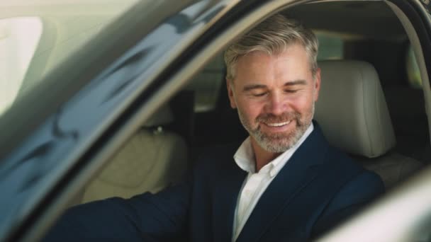 車のキャビンに座って 新しい車をテスト幸せな笑顔の男性の肖像画の広い角度 タッチボタン 指で指しています 成功したビジネスマンは運転席に座って購入を楽しむ — ストック動画