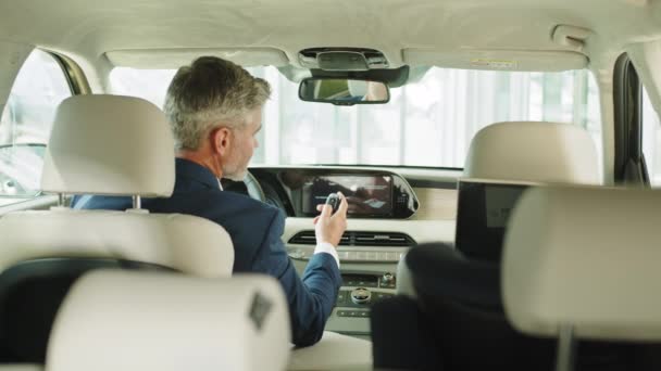 現代の新しい車の中で男を運転 鏡の中の顔に焦点を当てる 後ろの景色 車のショールームでミラーのビジネスマンの反射 — ストック動画