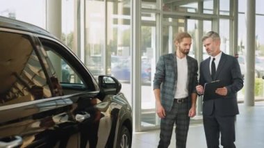 Başarılı orta yaşlı işadamı araba galerisinde erkek alıcıya araba satıyor. Araba satıcısı temsilcisi olan yakışıklı bir müşteri anlaşma yapıyor ve araba galerisinde anlaşma sözleşmesi imzalıyor.