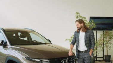 LVIV, UKRAINE - 20 Temmuz 2022: Showroom ve araba galerisi Hyundai. Yandan bakıldığında mutlu iş adamı erkek müşteri. Genç adam yeni arabaya bakıyor. Araba galerisinde tüketici