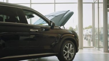 İş adamı araba kuaföründe araba seçiyor. Başarılı bir erkek müşteri siyah otomobilin kaputunu açıyor. Genç adam yeni arabaya bakıyor. Galerideki tüketici