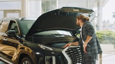 İş adamı araba kuaföründe araba seçiyor. Başarılı bir erkek müşteri siyah otomobilin kaputunu açıyor. Bir salonda bagajı açan düşünceli bir satış müdürü.
