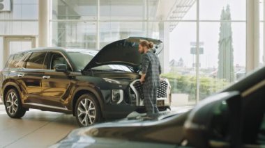 Satın alma seçiminde yeni bir arabaya karşı duran otomobil erkek müşterisinin satış mağazasından araba seçen yakışıklı bir işadamı. Araba galerisinde tüketici