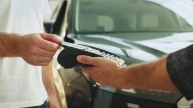 Kesilen adam müşteri müşterisi erkek elinde kablosuz banka ödeme terminali işlemleri kredi kartı ödemeleri araba galerisi araç galerisi galerisi galerisi galerisi araba galerisi araba galerisi motor fuarında otomobil satın aldı.