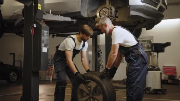 Dwóch Mężczyzn Zamontowało Koło Samochodu Podczas Montażu Opony Drodzy Mechanicy — Wideo stockowe