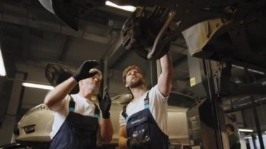 Otomobil merkezi galerilerindeki araba servisi konseptlerinin mekaniğini değiştiriyor. Bir araba atölyesinde çalışma. Tamirci araba servisinde çalışıyor. Aile işi konsepti