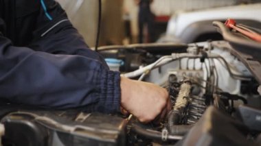 Otomotiv elektrikçisinin sigorta sistemi vasıtasıyla kontrol ve onarım aracının kaputunu tamir etmesinin yan görüntüsü. Güvenlik teftişi, ulaşım onarım garaj servis merkezi