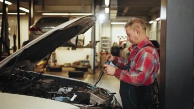 Otomotiv tamircisi bir araba kaputu aç ve motoru kontrol et. Çekici araç servisi yöneticisi tamirhanede çalışıyor. Atölyedeki otomobili tamir etmek için kontrol ve bakım yapıyor.