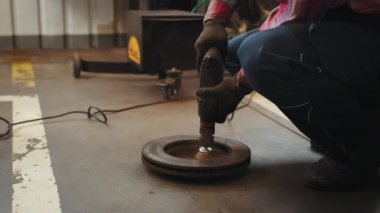Ekose gömlekli olgun orta yaşlı tamirci garaj dükkanında fren diski rotoru tekrar yüzeye çıkıyor. Yeni lastik değiştirme işlemi sırasında arabanın disk frenini temizliyorum. Garajda araba freni tamiri.