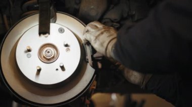 Profesyonel tamirci fren sistemini inceliyor. Arabadaki arızayı düzelt. Araba fren tamiri servisi. Pedlerin ve fren diskinin değiştirilmesi. Garaj dükkanında fren diski rotoru yeniden yüzeye çıkıyor.
