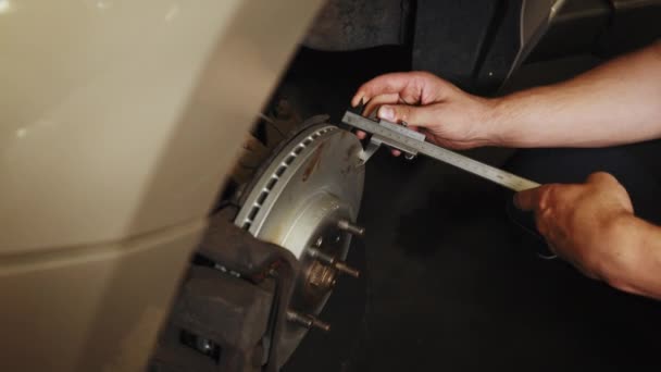 汽车维修 汽车制动盘更换专用设备在汽车修理厂或车库里 测量刹车盘的尺寸 测量制动盘磨损的卡尺 — 图库视频影像