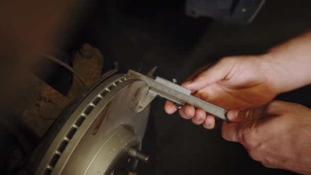 車サービス メンテナンス 特別な機器車の修理店やガレージで自動車ブレーキディスクの交換 ブレーキディスクの測定 ブレーキディスクの摩耗を測定するキャリパー — ストック動画