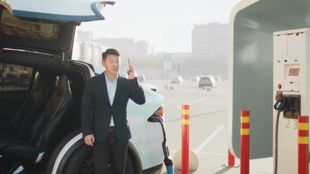 Succesvolle Aziatische Zakenman Met Een Mobiel Gesprek Afwachting Van Elektrische — Stockvideo