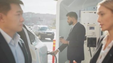 Özel bir yerde elinde meşrubatla elektrikli araç şarj eden yakışıklı, sakallı Hintli bir adam. Çok kültürlü iş arkadaşları iş meselelerini tablet ve akıllı telefon kullanarak ele alıyorlar.