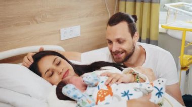 Çok ırklı bir çiftin hastane koğuşundaki yeni doğan bebeklerine bakışları. Anne baba hastane yatağında sarılıyor. Oğullarını seviyorlar.