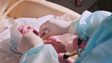 Hastanede yeni doğmuş bir bebek. Doğum uzmanı çocuk doktoruyum. Doktor, yeni doğmuş bir bebeği hayatın ilk birkaç dakikasında muayene eder. Hastanede yeni doğmuş bir bebek - yeni hayatın ilk dakikaları