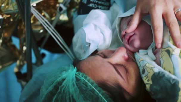母亲在医院里抱着新生儿 分娩后 母亲抱着刚出生的婴儿紧抱在胸前 第一眼看到妈妈和她的新生儿在手术室 现代医院手术室 — 图库视频影像