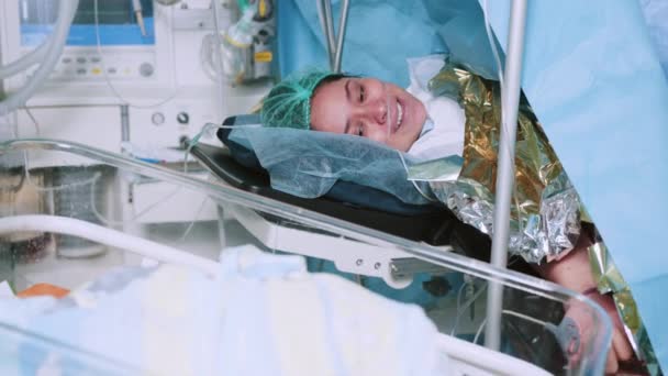 母亲在医院里抱着新生儿 分娩后 母亲抱着刚出生的婴儿紧抱在胸前 第一眼看到妈妈和她的新生儿在手术室 现代医院手术室 — 图库视频影像