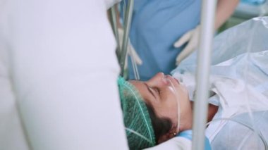 Ameliyat sırasında hastayı kapatın. Kadın anestezi altında masada yatıyor ve modern ameliyathanede solunum tüpüyle. Profesyonel cerrahlar hastayı laparoskopi aletleri kullanarak ameliyat ederler.