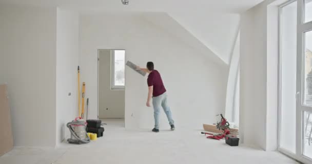 Mann Streicht Aktiv Die Wände Einer Geräumigen Hell Erleuchteten Wohnung — Stockvideo