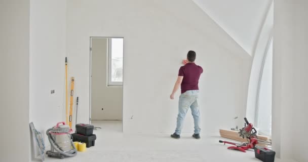 Człowiek Aktywnie Maluje Ściany Przestronnego Dobrze Oświetlonego Mieszkania Trakcie Remontu — Wideo stockowe