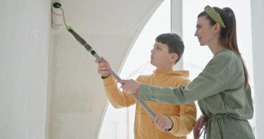 Bir anne ve genç oğlu birlikte çalışıyorlar. Bir aile, yeni bir dairede parlak beyaz bir duvar boyayarak ev geliştirme projesine katılıyor. DIY ruhunun ve aile bağının özünü yakalar.