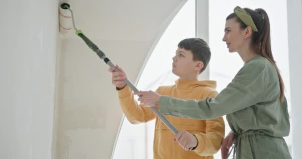 一个母亲和她十几岁的儿子一起工作 一个家庭参加了一个家庭装修项目 在新公寓里粉刷一道明亮的白墙 捕捉Diy精神和家庭联系的本质 — 图库视频影像