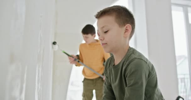 Два Мальчика Активно Участвуют Проекте Ремонту Дома Красят Стены Новой — стоковое видео