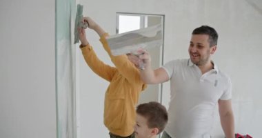 Ev yenileme projesi sırasında bir baba ve çocuklarının yeni dairelerinin duvarlarını şakayla boyadığı bir aile anı. Takım çalışması ve yeni bir başlangıcın tazeliği..