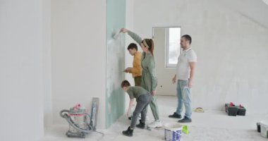 Yeni Evi Yenileme, Geniş Odadaki Duvarları Boyama. Dört kişilik bir aile, duvarları birlikte boyayarak yeni dairelerinin yenilenmesinde aktif rol oynuyor. Takım çalışması gösteriliyor