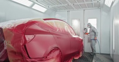 Otomotiv teknisyeni araba bakım merkezindeki özel bir odaya sprey boyayla araba boyuyor. Düzgün bir son için uzman araba boyama işlemi devam ediyor. Bir Araca Boya Uygulayan Araba Boyacısı