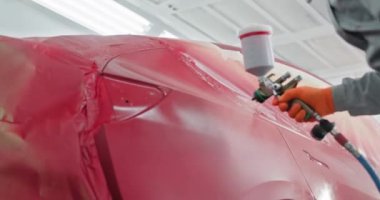 Profesyonel bir işçi araba tamirhanesinde özel bir araba bölmesinde sprey boyayla araba boyuyor. Kaliteli araba boyama ve araba tamiratı. Otomotiv boyama hizmetleri kavramı