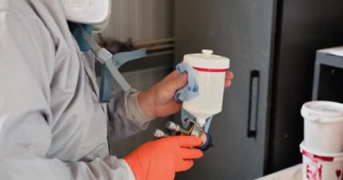 Korumalı ekipmanlı otomotiv teknisyeni bir benzin istasyonunda araba tamirine boya hazırlıyor. Sprey tabancaya ve boya kutusuna odaklan. Otomotiv Teknisyeni Araba Tamiri İçin Boyayı Hazırlıyor