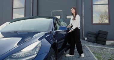 Müşteri onun elektrikli arabasını garajdan alır. Zarif bir bayan müşteri atölye yakınında elektrikli bir arabaya biner, belki. Yeşil enerji ve araç bakım kavramı