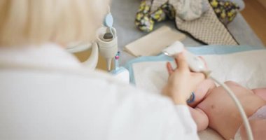 Yeni doğan bebeğe klinikte karın ultrasonu yapan doktor. Klinikte modern tıbbi gereçler kullanan yeni doğmuş bir bebek üzerinde karın ultrasonu testi yapan bir doktor.