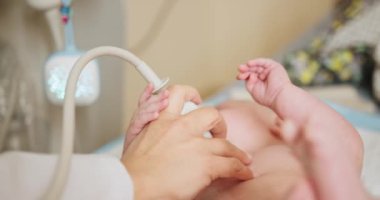 Pediyatrist, Yeni Doğan Bebek 'e Abdominal Ultrason yapıyor. Bir pediyatrist modern tıbbi ekipmanlar kullanarak yeni doğmuş bir bebeğe ultrason uygular. Profesyonel sağlık hizmetleri.