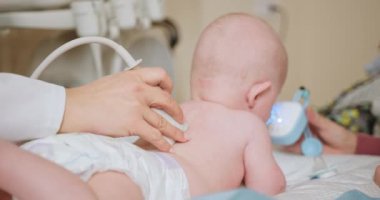 Yeni doğan bebek kliniğinde ultrason muayenesi yapan doktor. Bir çocuk doktoru yeni doğmuş bir bebeği hastanede muayene etmek için ultrason cihazı kullanır. Sağlık ve tanı konsepti.