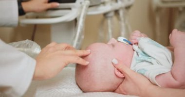 Doktor, yeni doğan bebeğe ultrason yapıyor. Bir pediyatrist, yeni doğmuş bir bebeğe gelişmiş tıbbi ekipmanlarla klinik ortamda karın ultrasonu yapar..