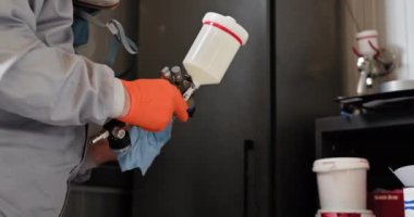 Otomotiv teknisyeni araba tamiri için boya hazırlıyor. Korumalı ekipmanlı otomotiv teknisyeni bir benzin istasyonunda araba tamirine boya hazırlıyor. Sprey tabancaya ve boya kutusuna odaklan.