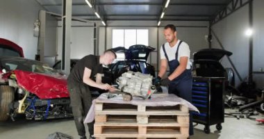 Tamirciler Oto Tamirhanesinde Elektrikli Otomobil Motoru üzerinde çalışıyorlar. Profesyonel bir oto atölyesinde parçalanmış bir elektrikli araba motoru üzerinde çalışan iki tamirci bakım ve onarım sağlıyorlar. EV servisi.