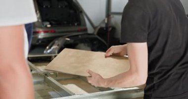 Atölyede EV Araç Batarya Modülü Teknisyeni. Bir teknisyen atölyedeki bir EV araba akü modülünü dikkatlice yönetir ve en iyi performansı sağlar. Otomobil Servisi, Elektrikli Araba Aküsü Taşıma.